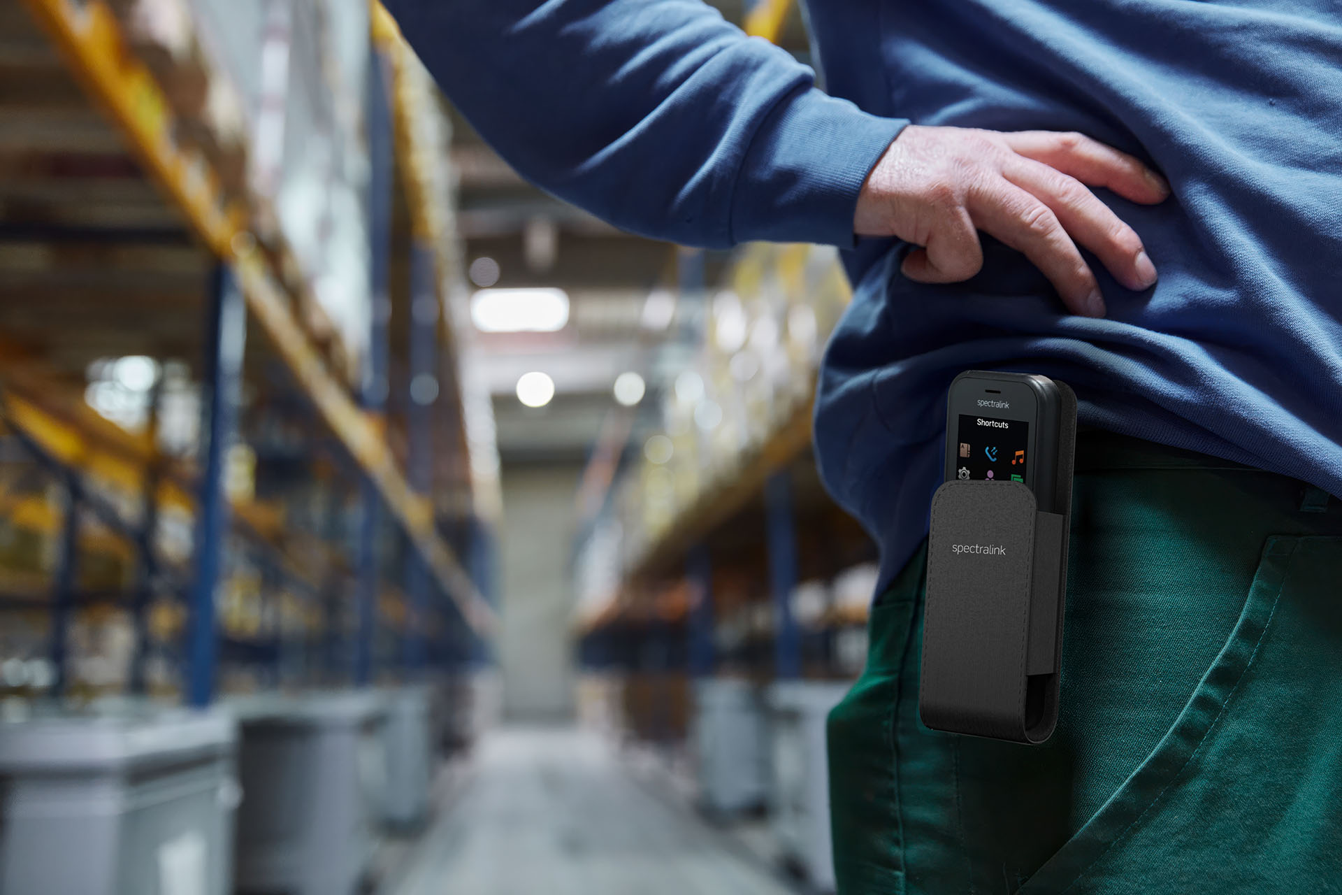 An employee in a warehouse with a portable cell phone in a belt pouch
