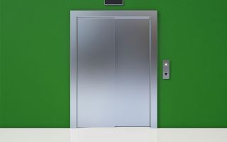 Geschlossene Aufzugstür in einer grüngestrichenen Wand