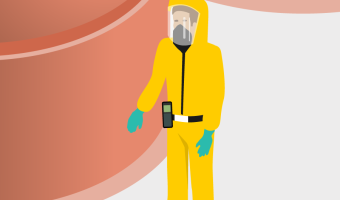 Employee in yellow protective suit stands in front of silos