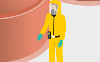 Mitarbeiter in gelbem Schutzanzug steht vor Silos